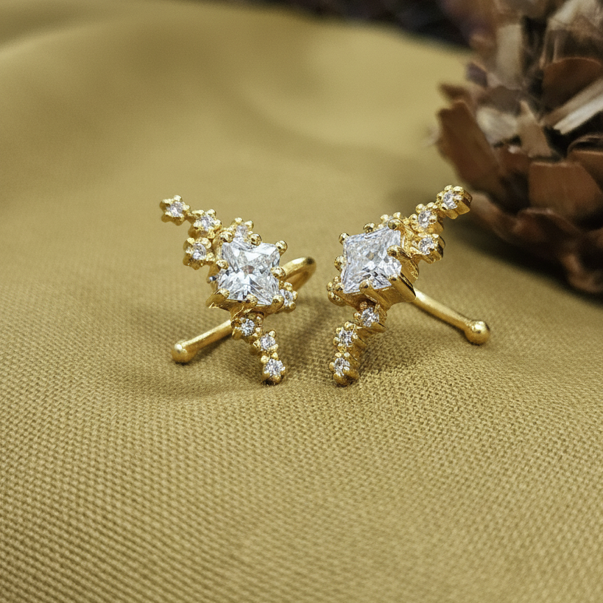 Gold earrings with diamond-like stones on a textured gold surface